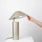 Adjustable cone shade steel table lamp, in Champagne Gold, a hand adjusting the shade