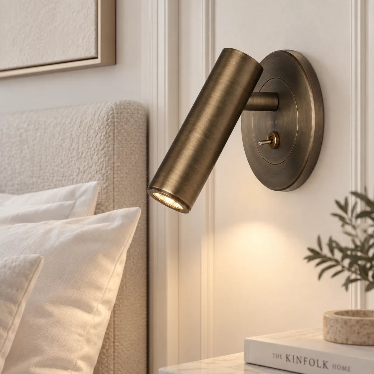 Adjustable reading wall light, in bronze beside a bed