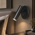 Adjustable reading wall light, in black beside a bed