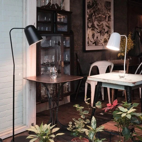 Adjustable shade steel floor lamp in black, beside a table in a dark room