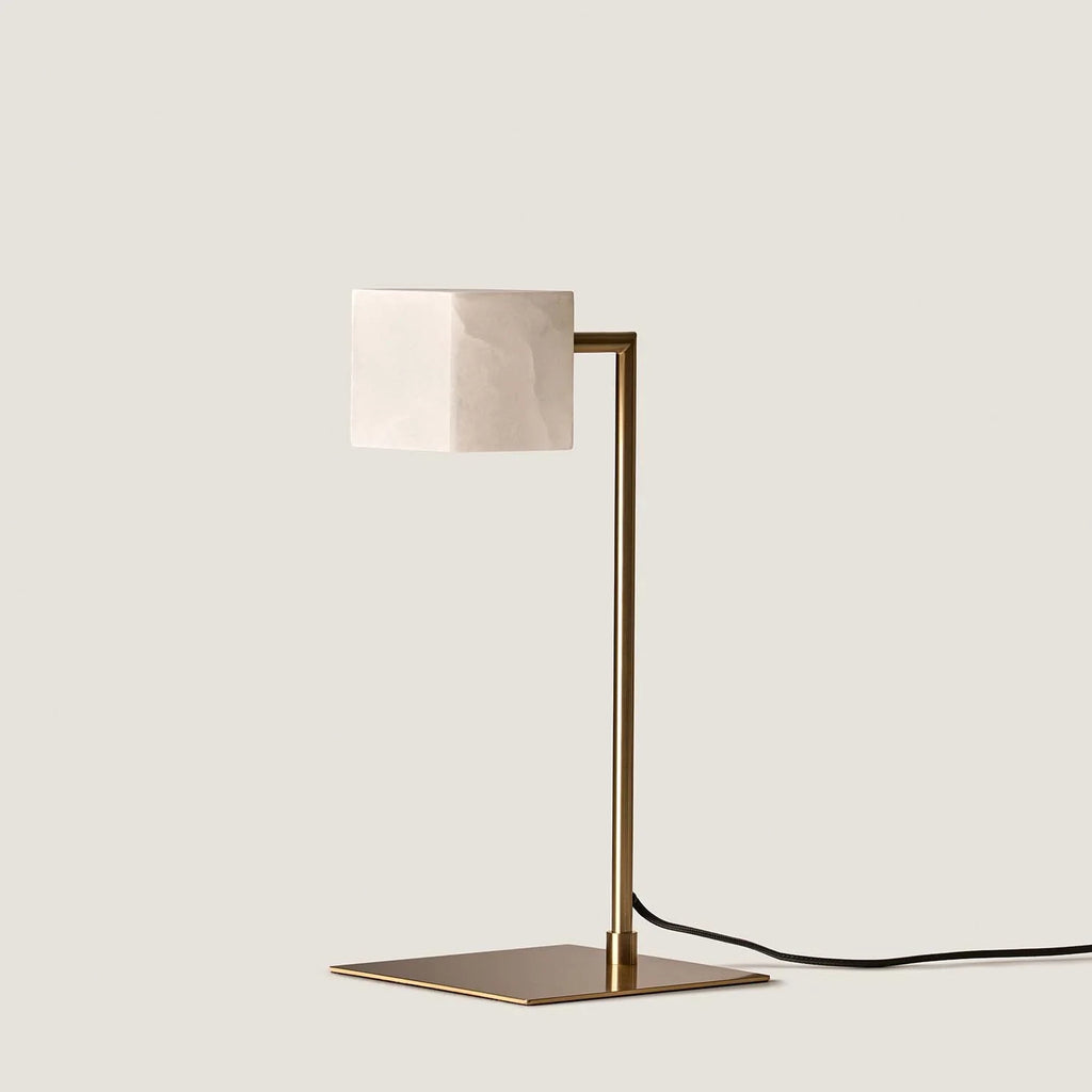 Alabaster cube table lamp with square stem, in aged gold, unlit, on a plain background