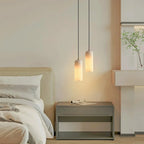 Alabaster cylinder pendant light, a pair beside a bed