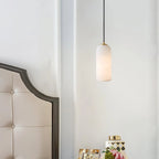 Alabaster cylinder pendant light, beside a headboard