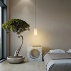 Alabaster cylinder pendant light, in a bedroom with a bonsai