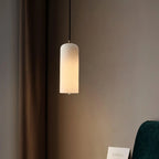 Alabaster cylinder pendant light, lit, close to a wall