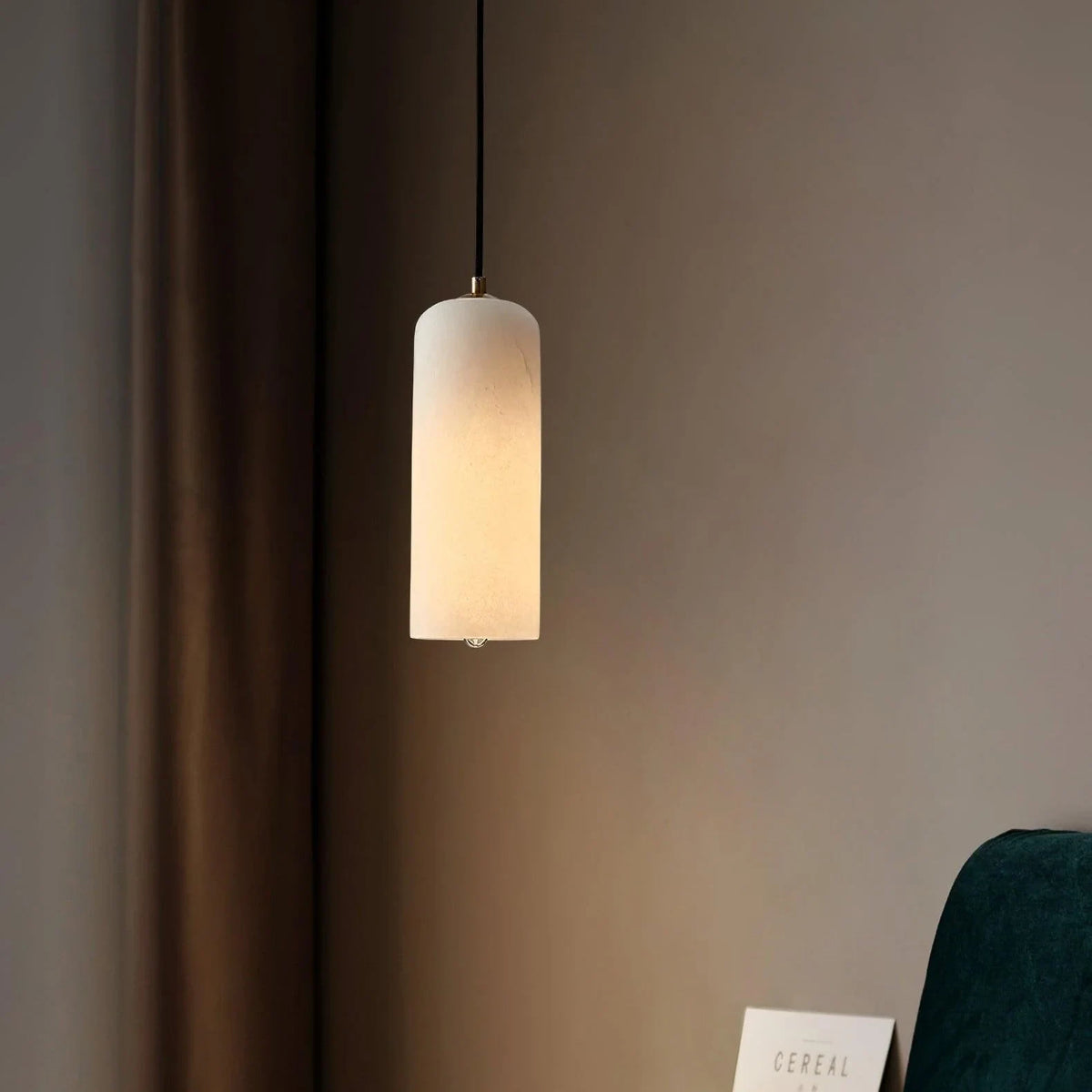 Alabaster cylinder pendant light, lit, close to a wall