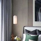 Alabaster cylinder pendant light, beside a bed