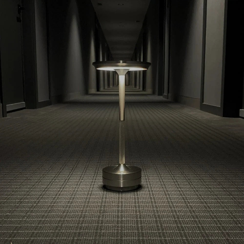 Aluminium cordless table lamp, lit in a room setting