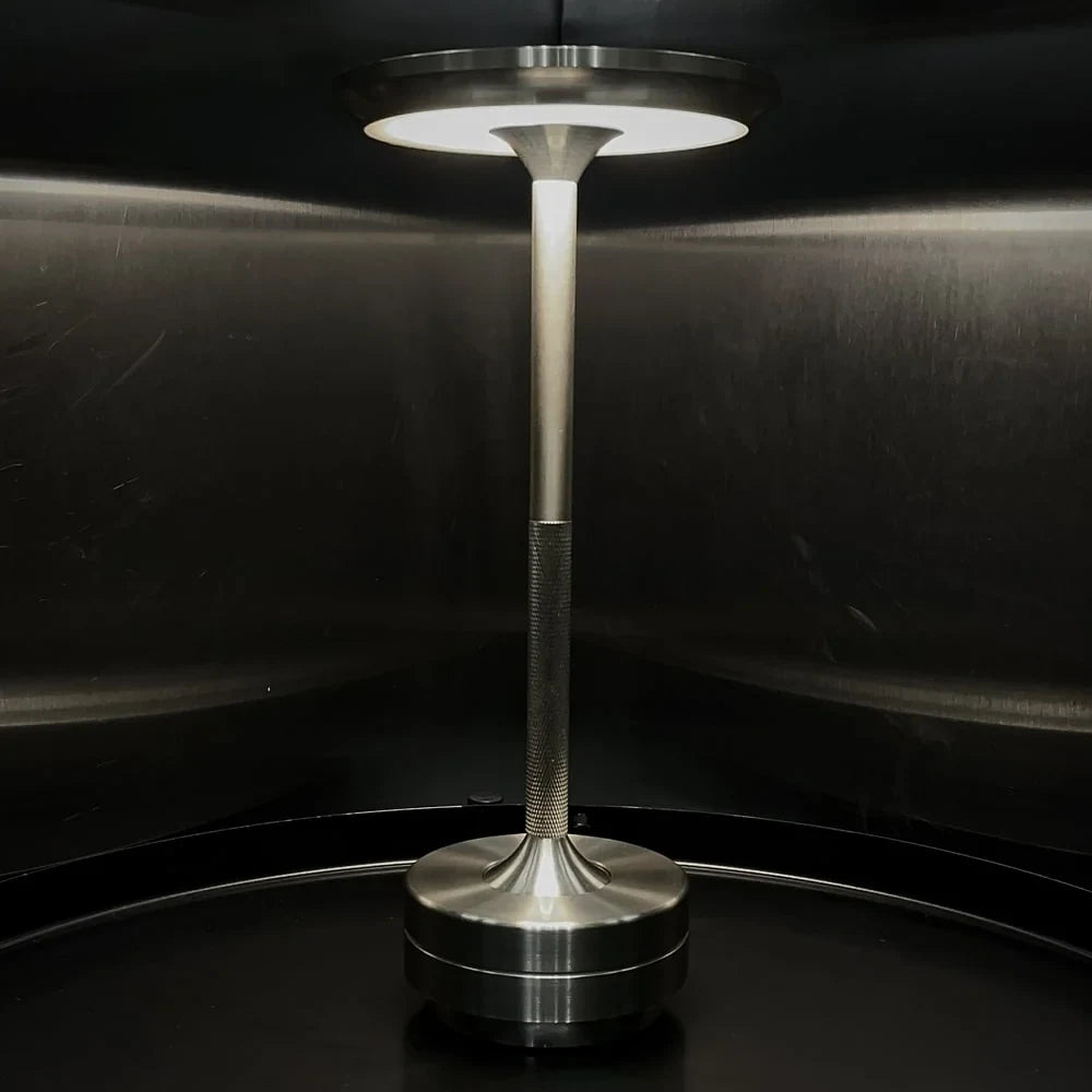 Aluminium cordless table lamp, lit in a room setting