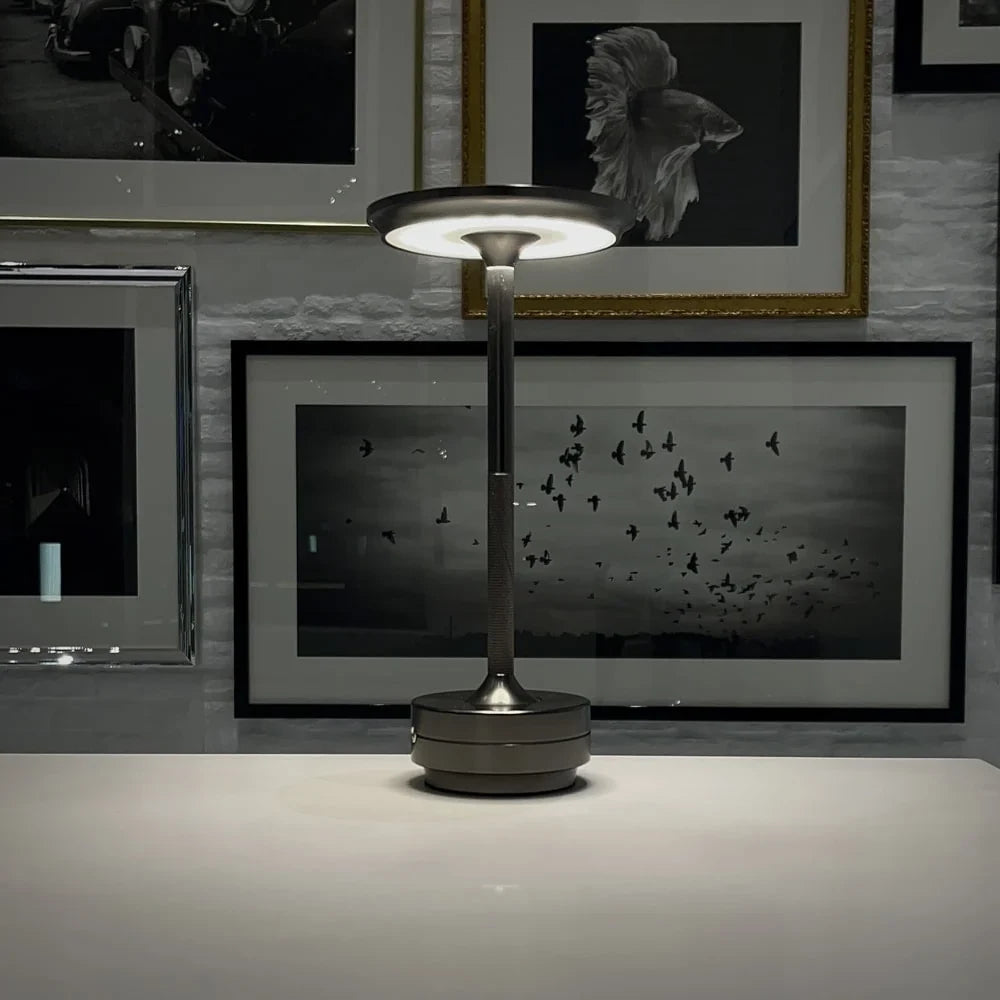 Aluminium cordless table lamp, lit in a room setting