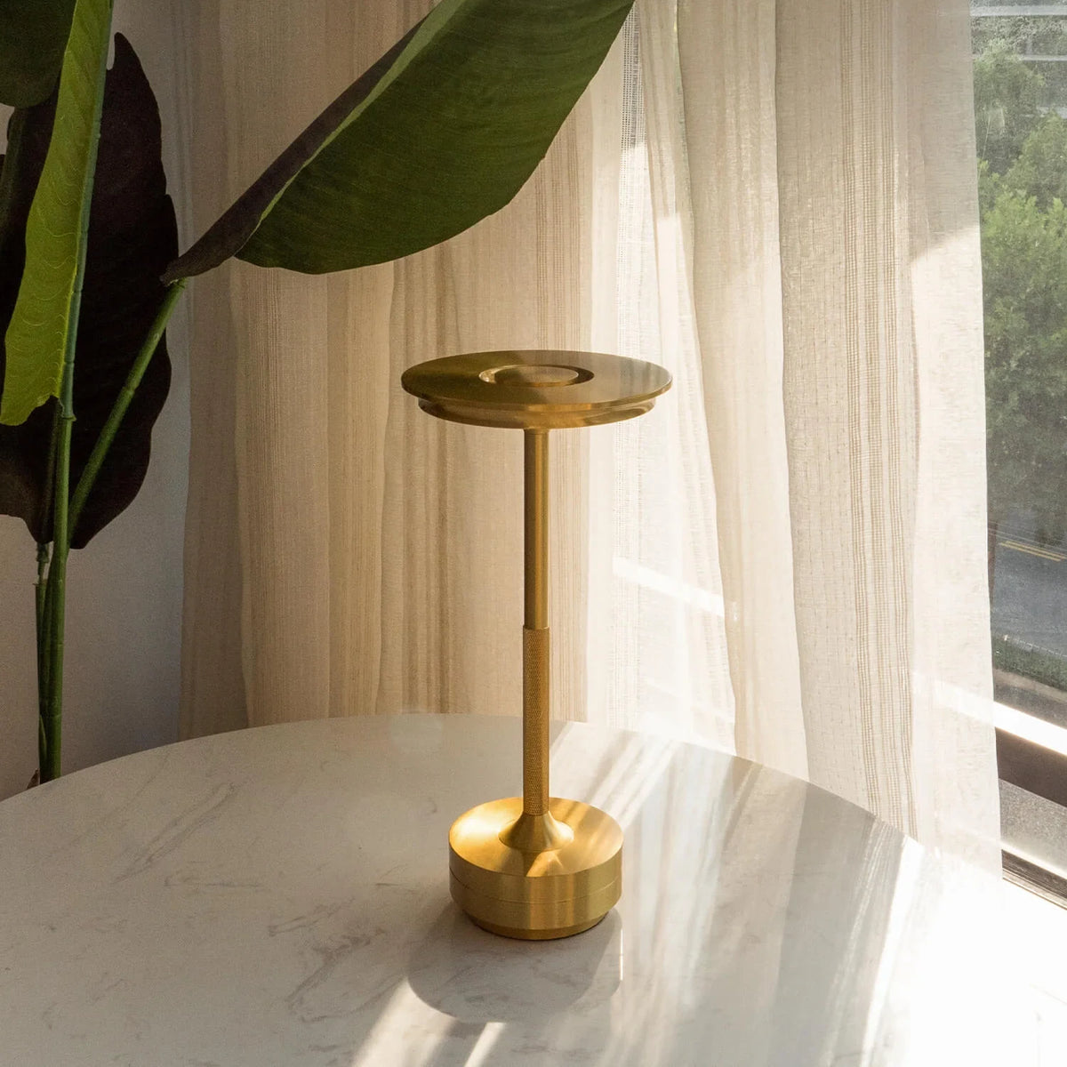 Aluminium cordless table lamp, lit in a room setting
