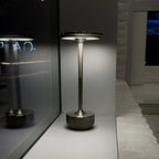 Aluminium cordless table lamp, lit in a room setting
