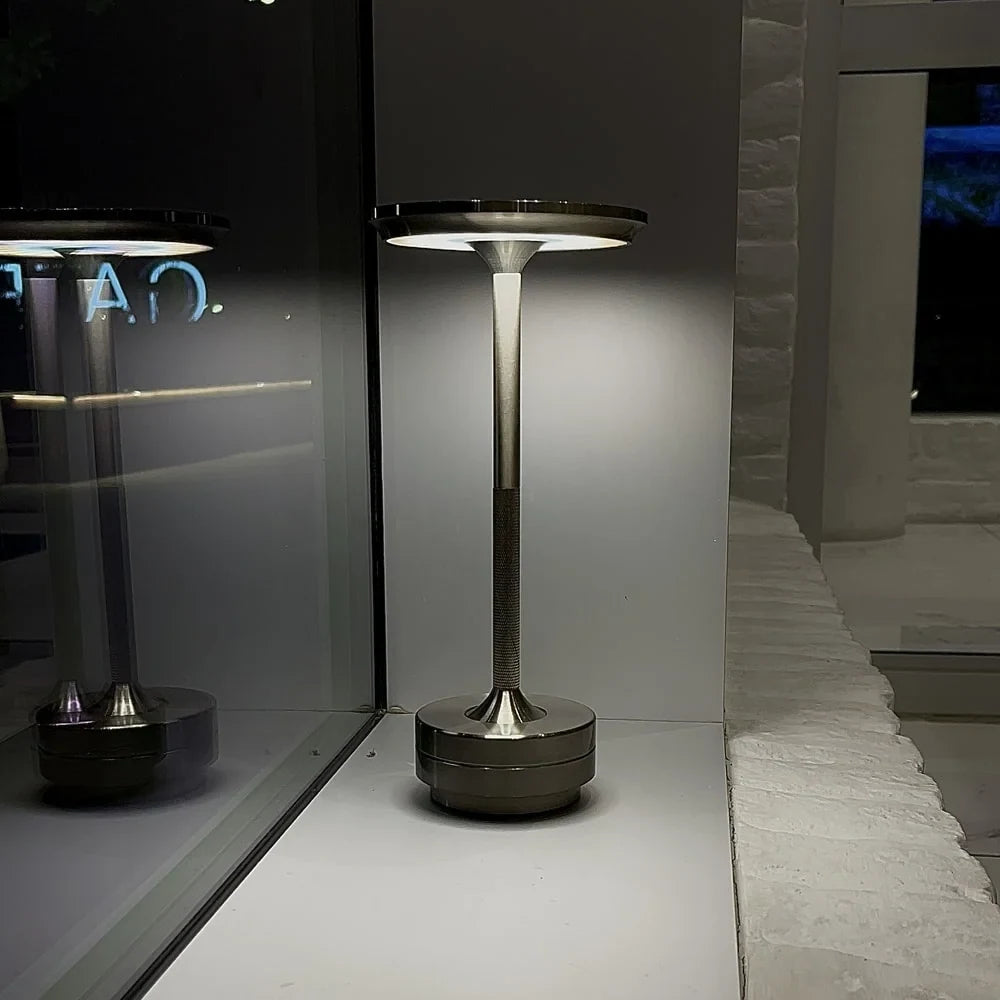 Aluminium cordless table lamp, lit in a room setting