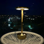 Aluminium cordless table lamp, lit on a balcony at night