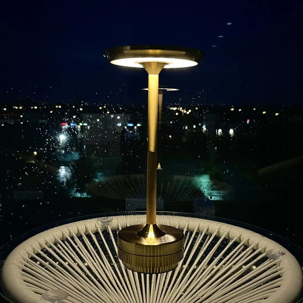 Aluminium cordless table lamp, lit on a balcony at night