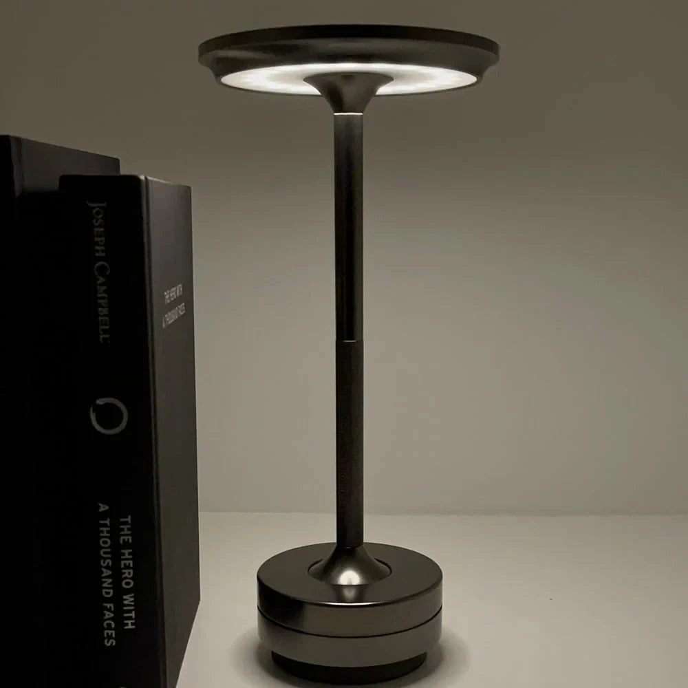 Aluminium cordless table lamp, lit in a room setting