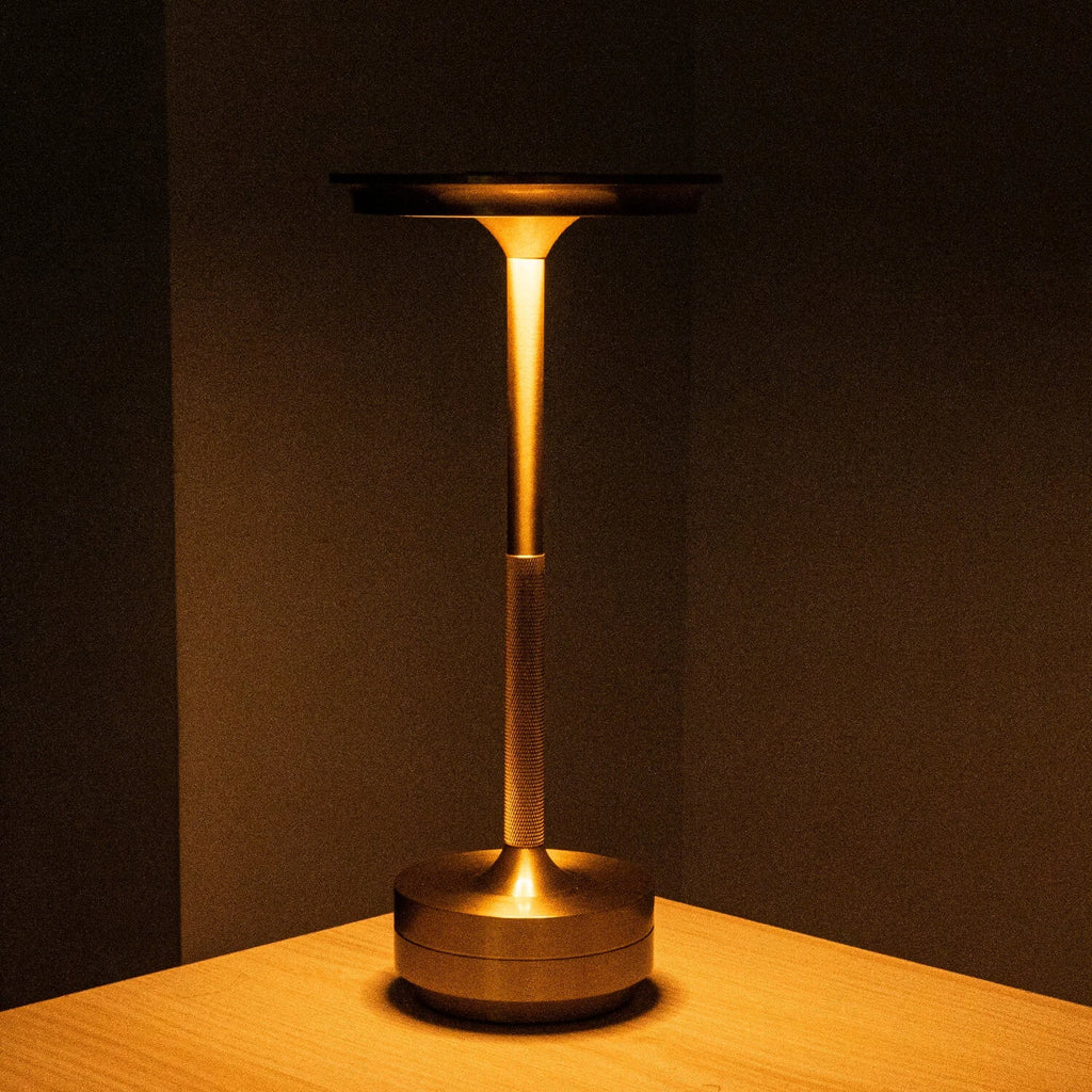 Aluminium cordless table lamp, lit in a room setting