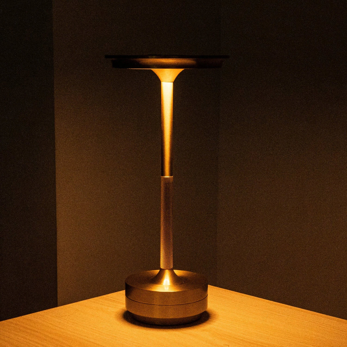 Aluminium cordless table lamp, lit in a room setting