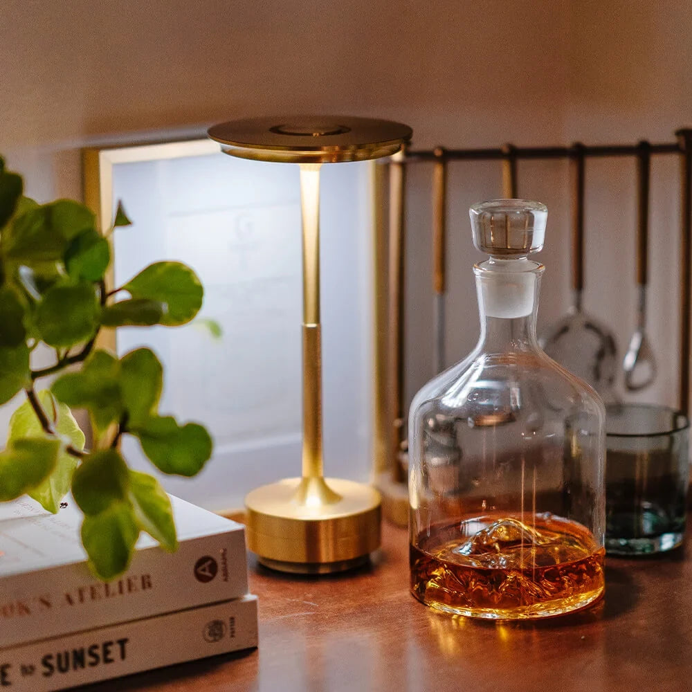 Aluminium cordless table lamp, lit in a room setting