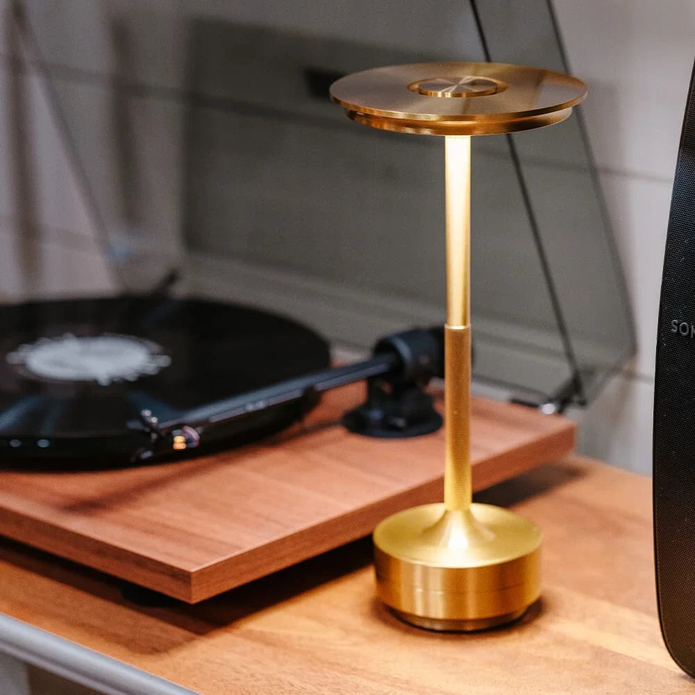 Aluminium cordless table lamp, lit beside a record player