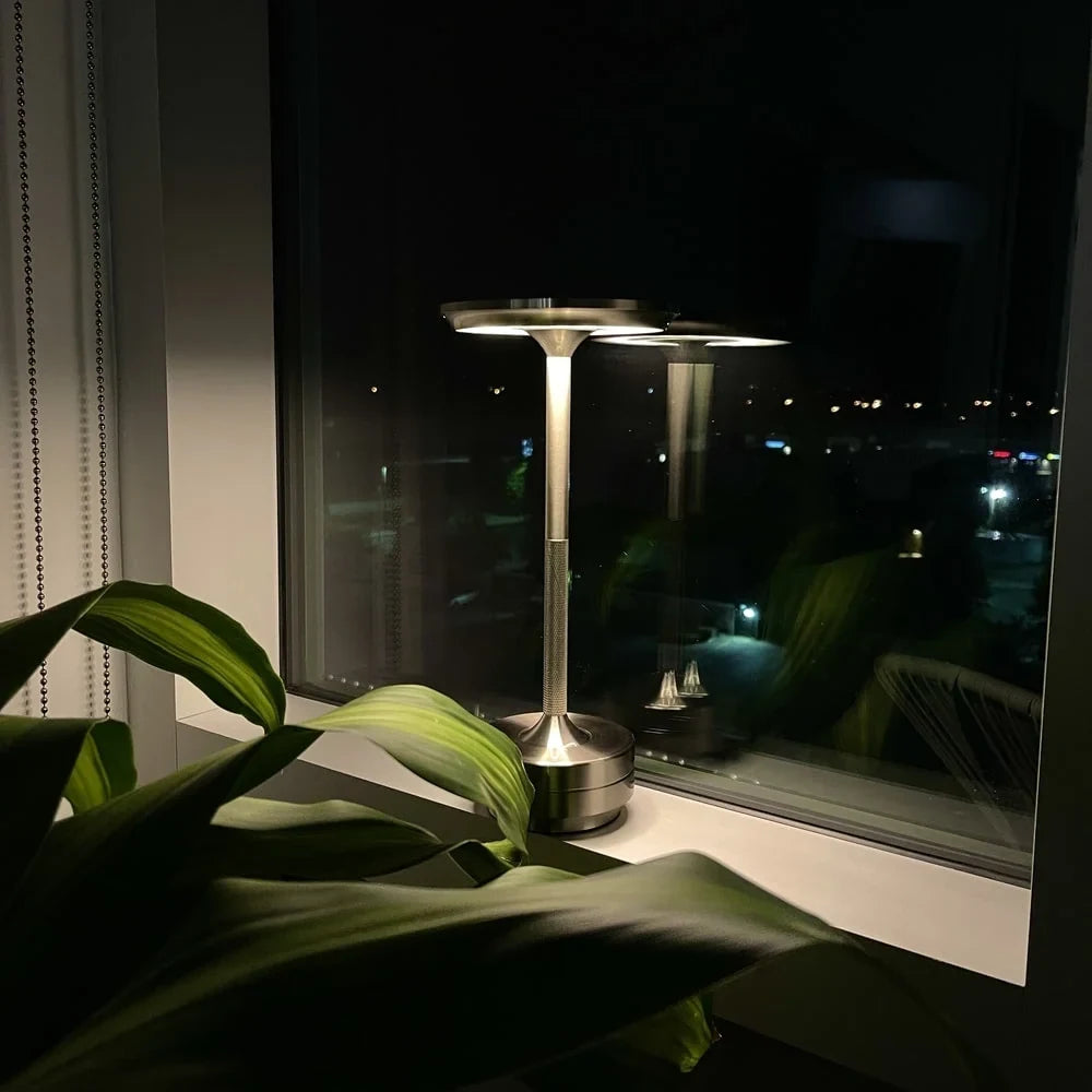 Aluminium cordless table lamp, lit in a room setting