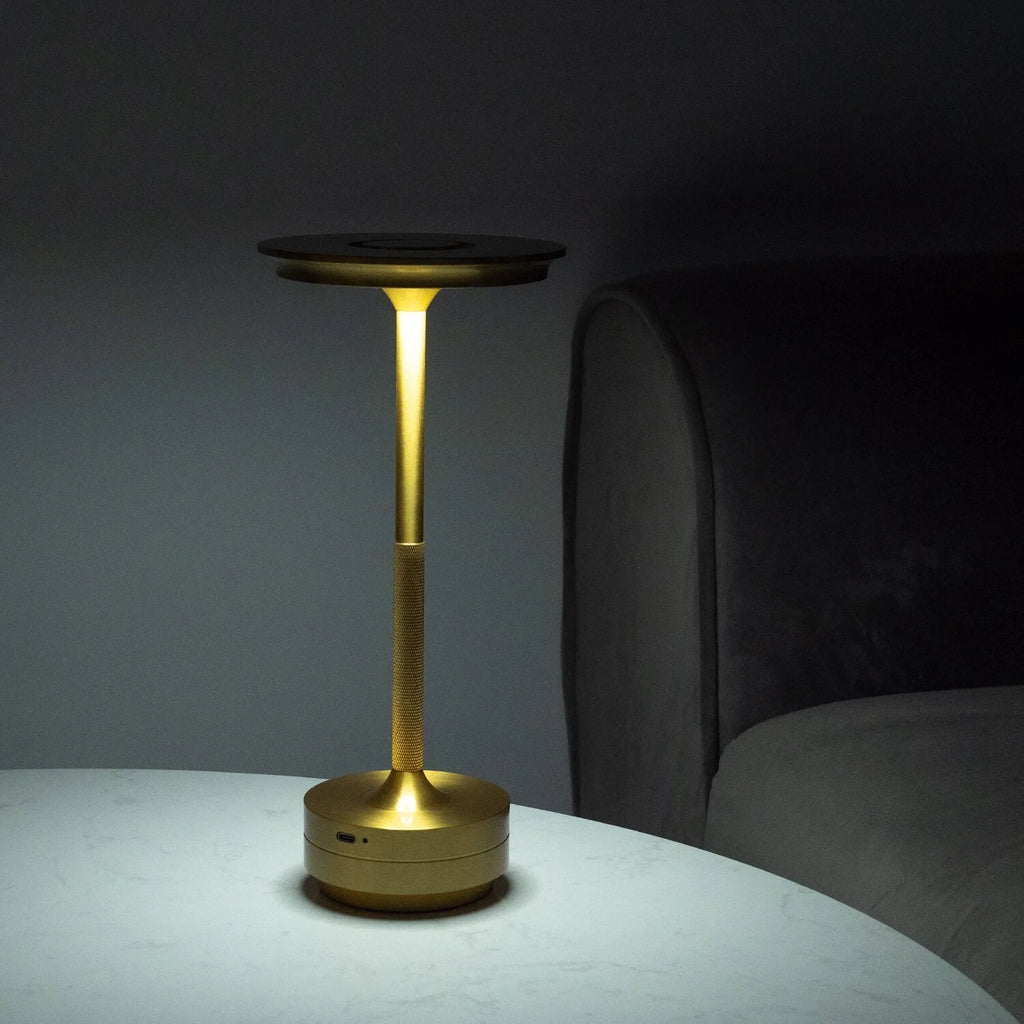 Aluminium cordless table lamp, lit in a room setting