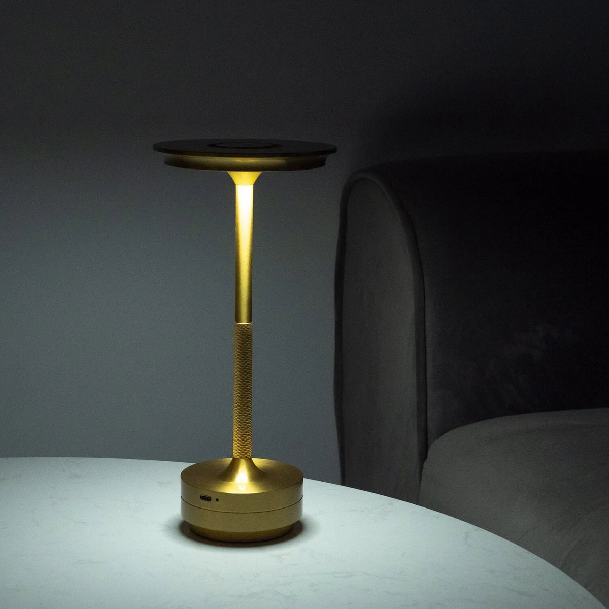 Aluminium cordless table lamp, lit in a room setting