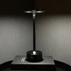 Aluminium cordless table lamp, lit in a room setting