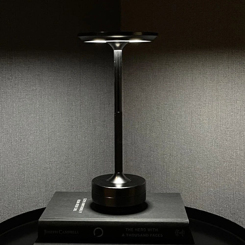 Aluminium cordless table lamp, lit in a room setting