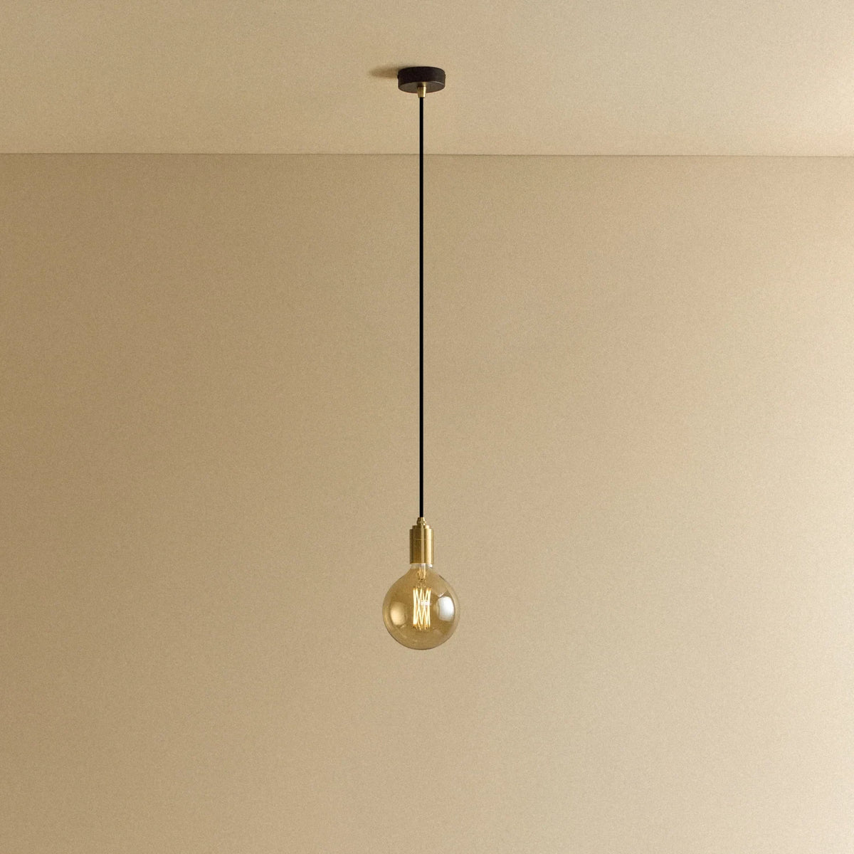 Amber filament globe bulb pendant, lit against a plain wall