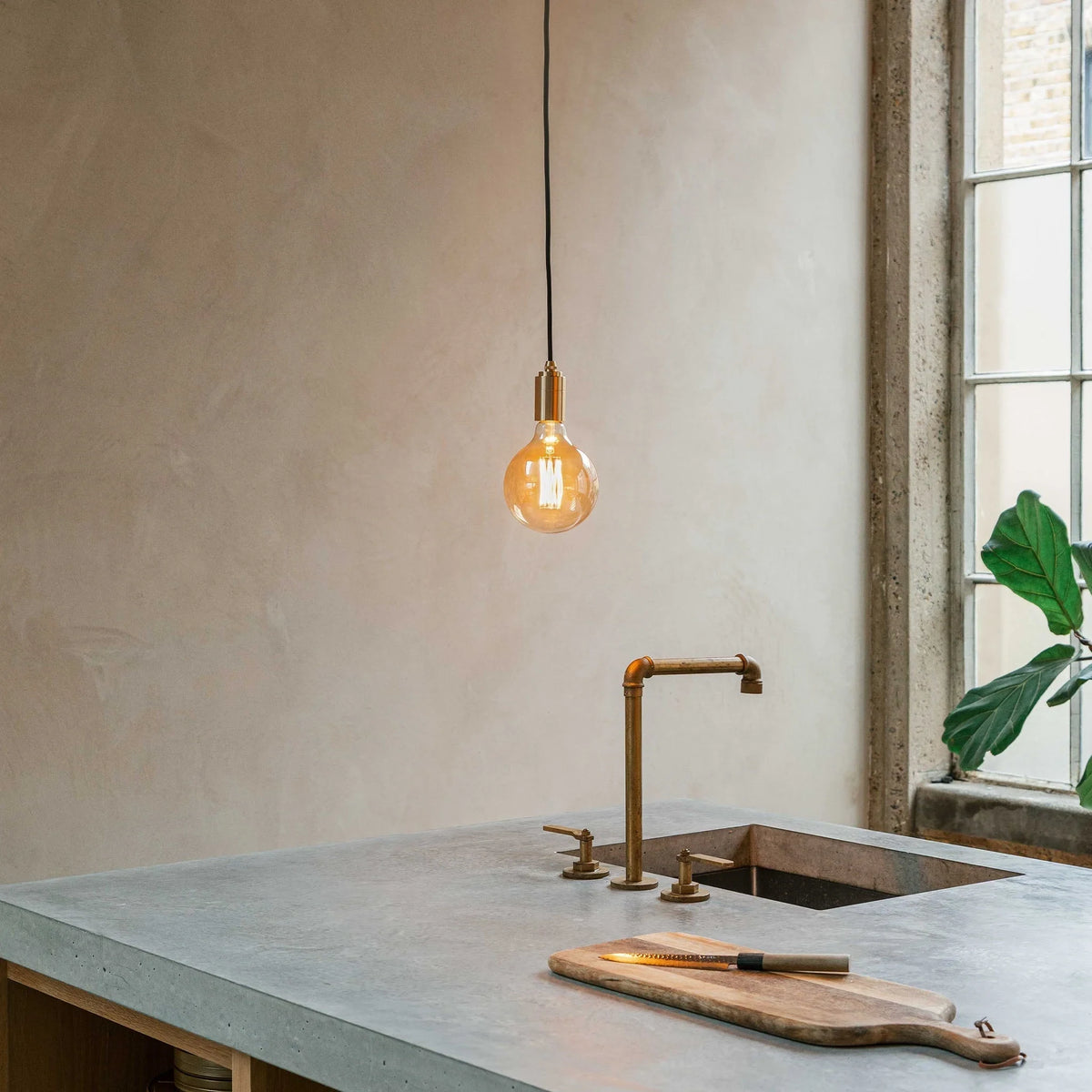 Amber filament globe bulb pendant, above a kitchen worktop