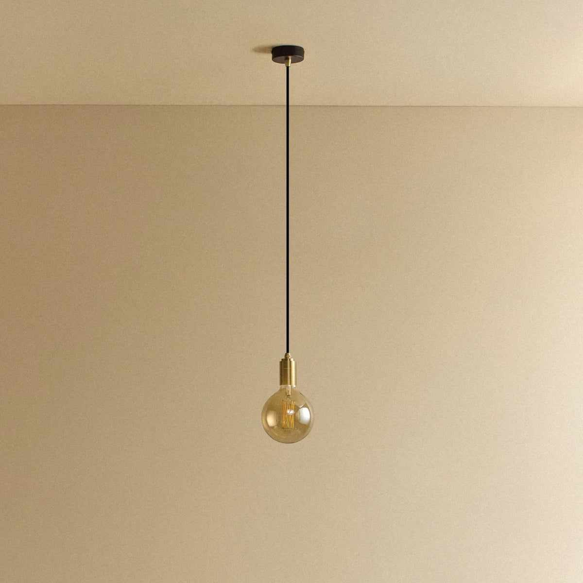 Amber filament globe bulb pendant, unlit against a plain wall