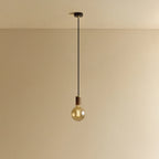 Amber Filament Globe Bulb Pendant, in walnut, lit, against a plain wall