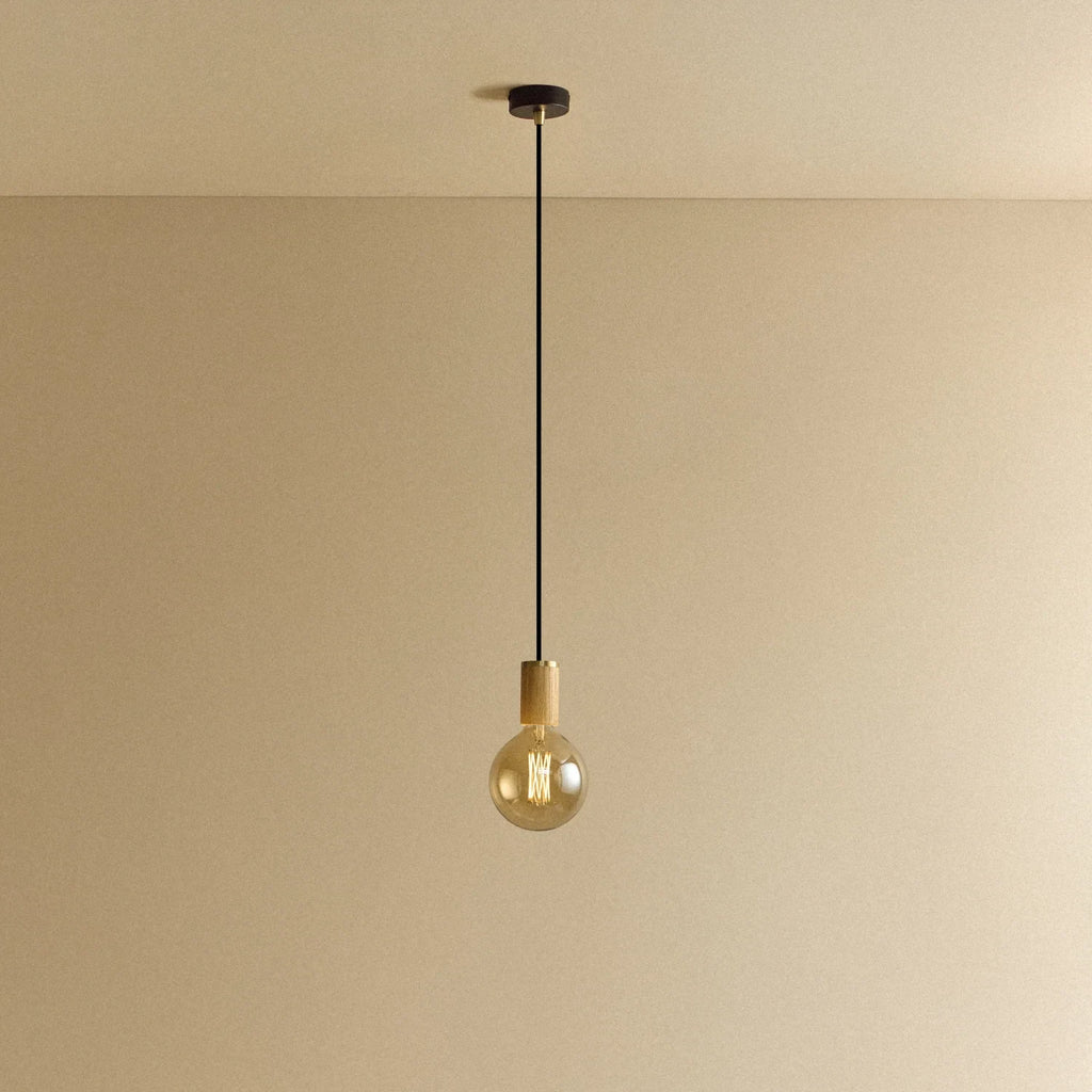 Amber tinted globe filament pendant, oak, lit, against a plain wall