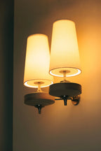 Walnut and antique brass wall light, double, lit at night