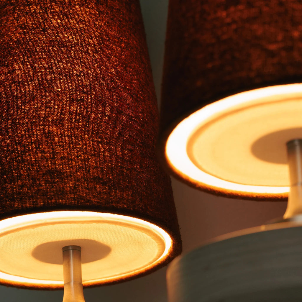 Walnut and antique brass wall light, close-up of the lit fabric shades