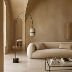 Arc floor lamp with a ribbed lantern shade and black marble foot, behind a sofa in a living room