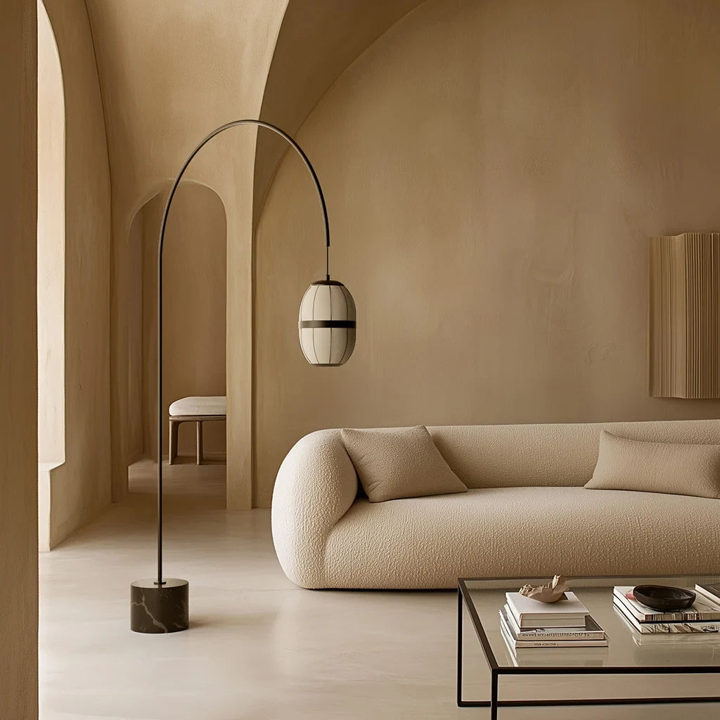 Arc floor lamp with a ribbed lantern shade and black marble foot, behind a sofa in a living room
