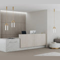 Arch pendant with twin ribbed glass tubes, in aged gold above a reception desk