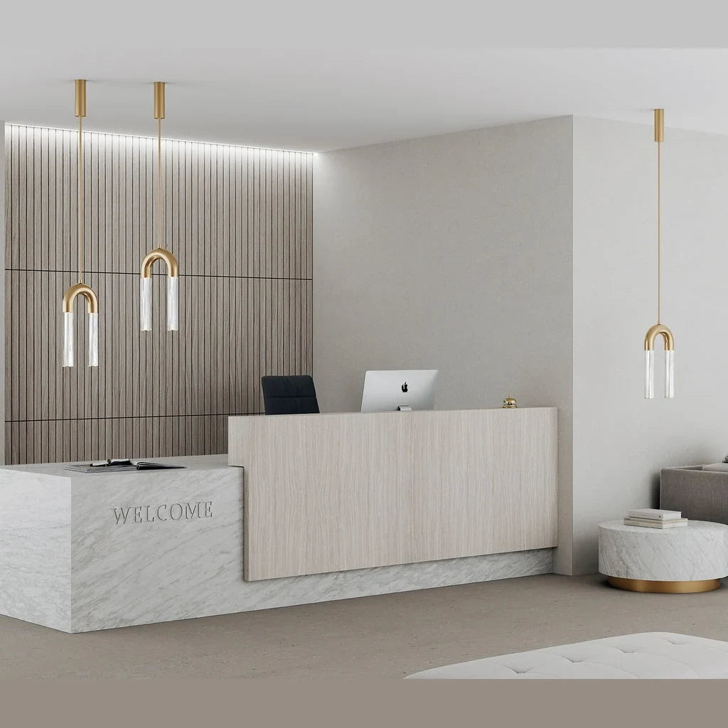Arch pendant with twin ribbed glass tubes, in aged gold above a reception desk