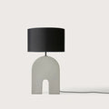 Arched ceramic table lamp base in ash grey, with a black drum shade (shade not included)