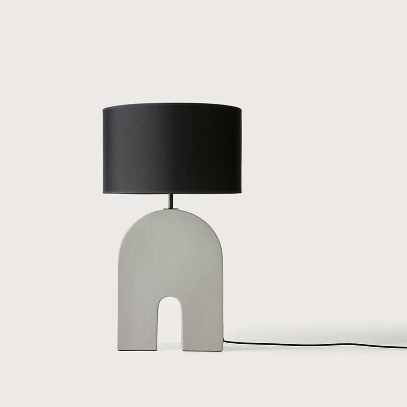 Arched ceramic table lamp base in ash grey, with a black drum shade (shade not included)