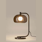 Arched table lamp with domed shade, lit, with smoked glass