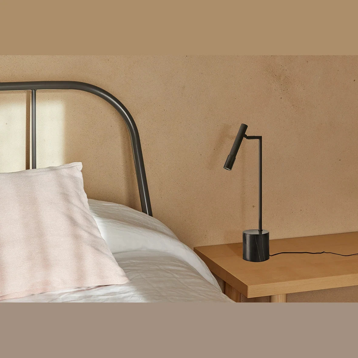 Articulated LED reading table lamp, black marble base, on a bedside table