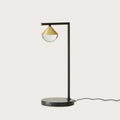 Black marble table lamp with a brass cone and optic glass diffuser, against a plain background
