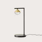 Black marble table lamp with a brass cone and optic glass diffuser, against a plain background
