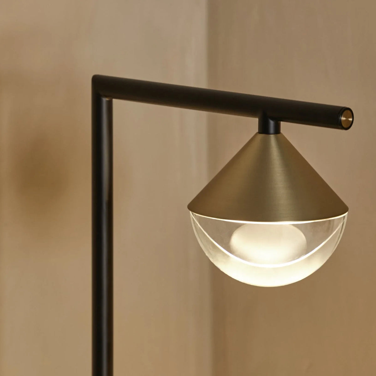 Black marble table lamp with a brass cone and optic glass diffuser, close-up of the lit brass cone and glass diffuser