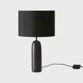 Marble pill-shaped table lamp, in black marble, with a black shade (sold separately), on a plain background