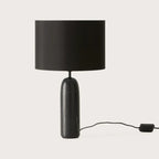 Marble pill-shaped table lamp, in black marble, with a black shade (sold separately), on a plain background