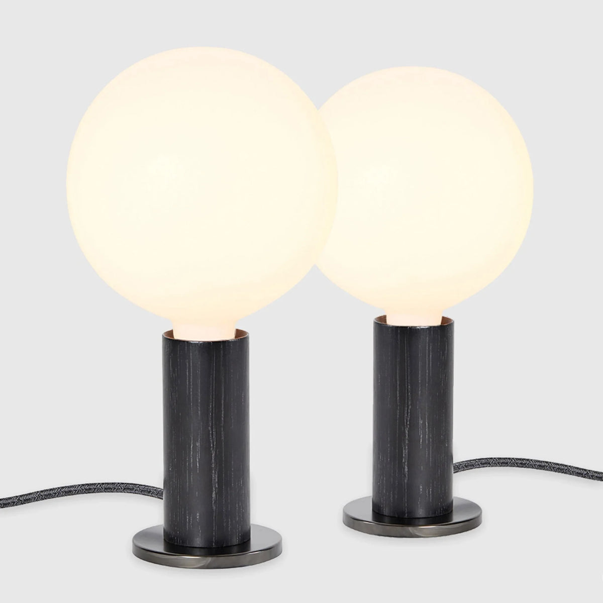 Blackened oak table lamp pair, opal globe bulbs, on a white background